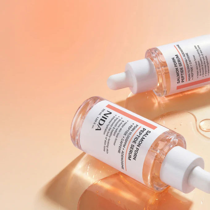 Two NIDA skincare serum bottles with droppers on a gradient background